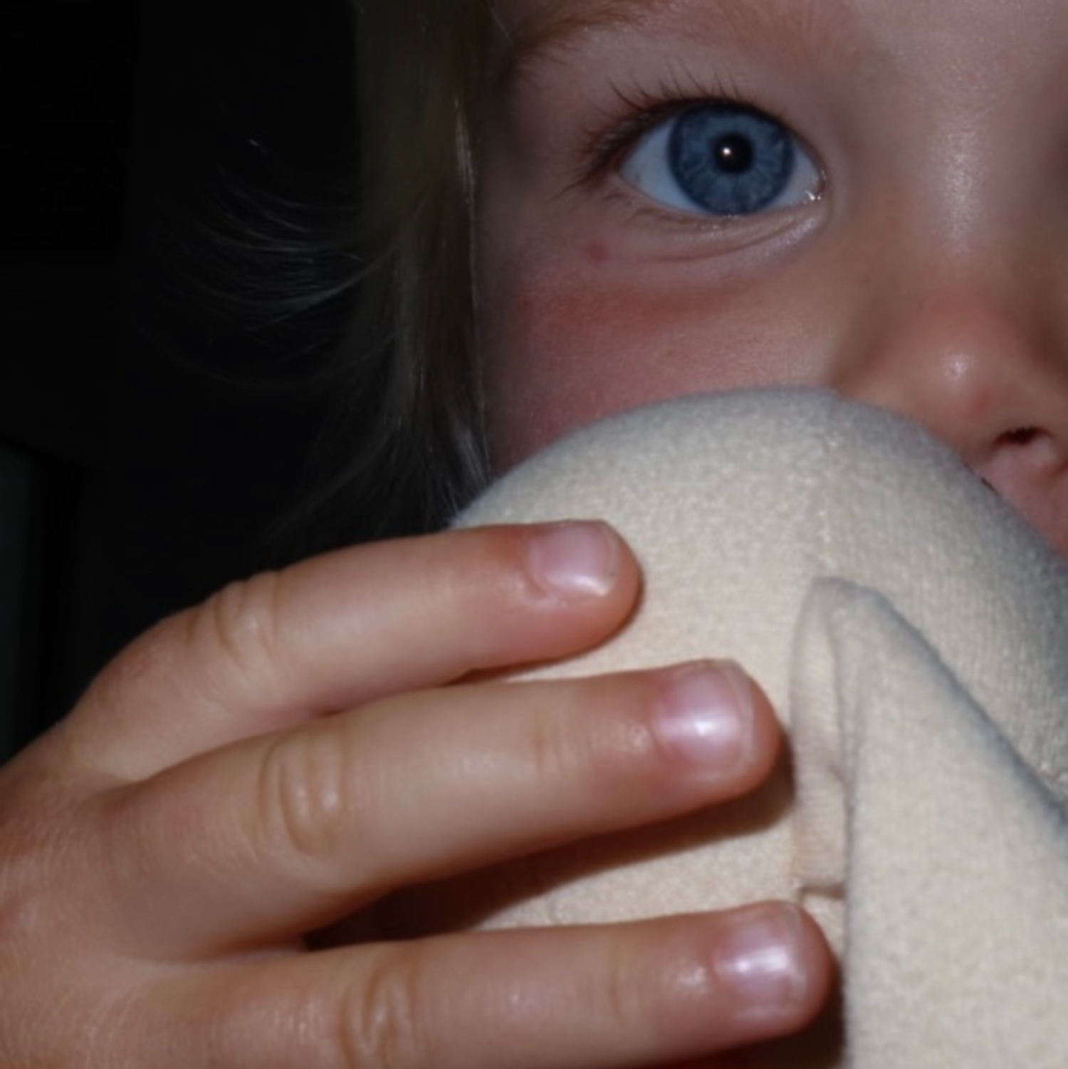 Close-up of a child holding a white object close to their face.