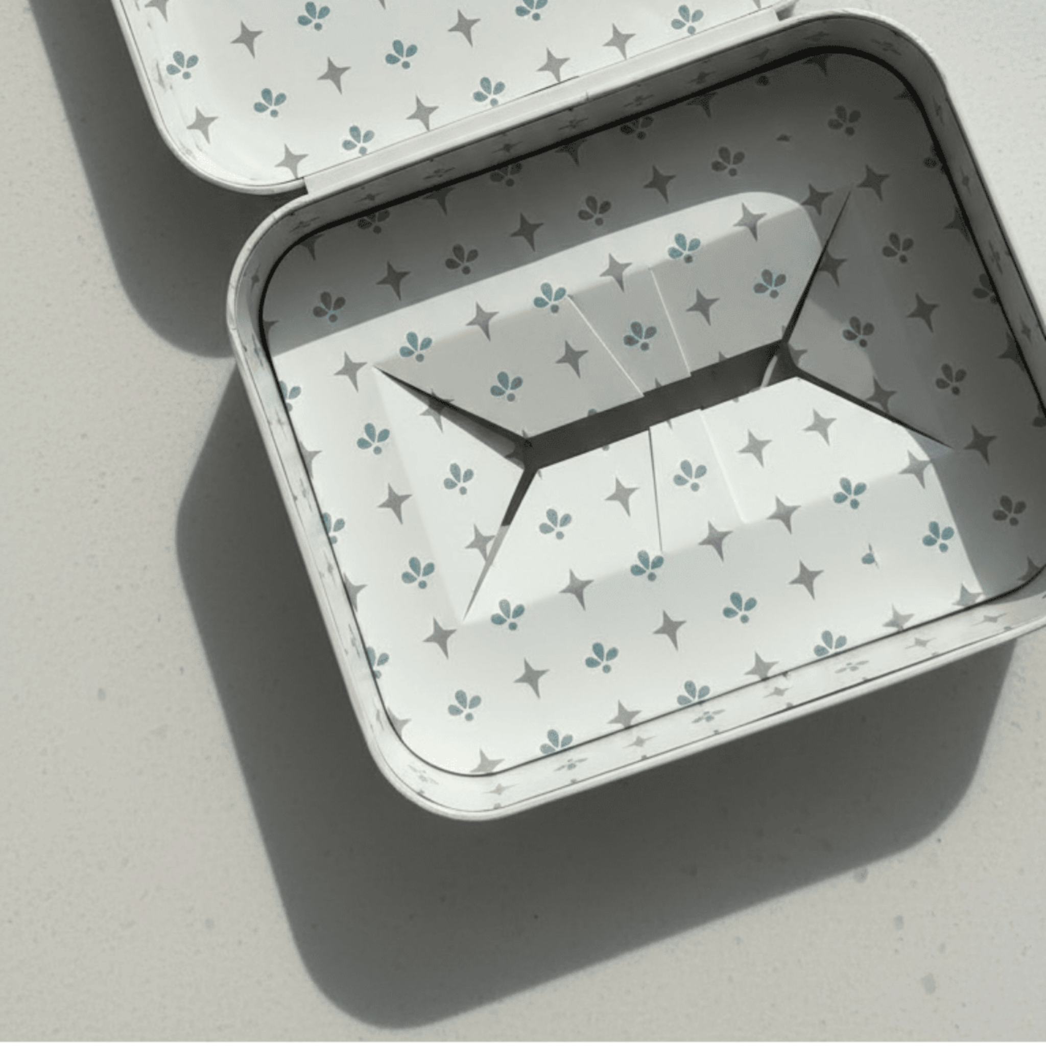Metallic tin with a star pattern on a light gray background