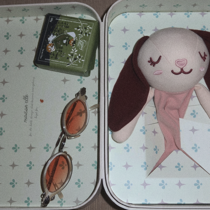 open maison elle keepsake suitcase holding a sleepy elle softie, sunglasses and small keepsakes